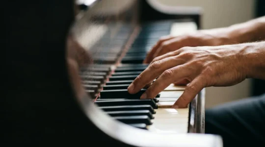Close-up of musician's hands on piano keys with shallow depth of field emphasizing musical expression